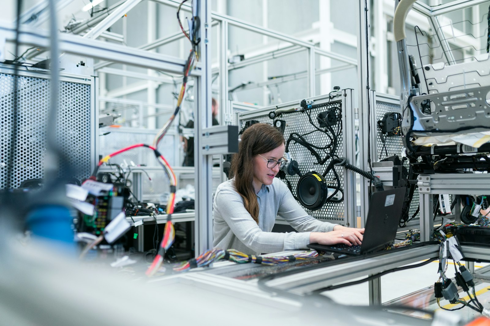 An engineer working on a laptop beside a production line